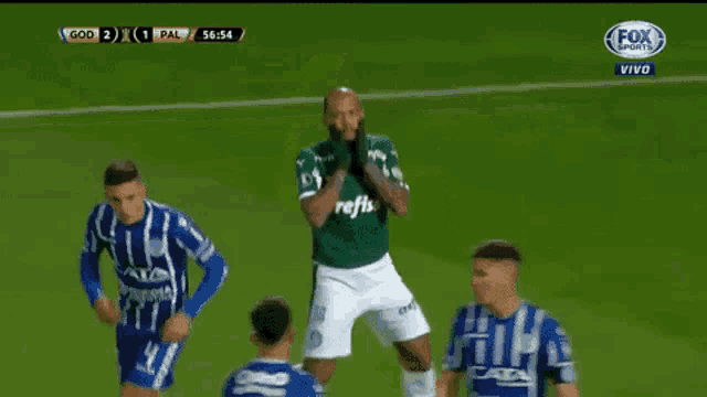 a soccer player in a green and white uniform is running on a field .