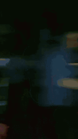 a man with glasses is dancing in a dark room