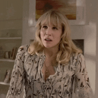 a woman with blonde hair and a floral shirt is standing in a room