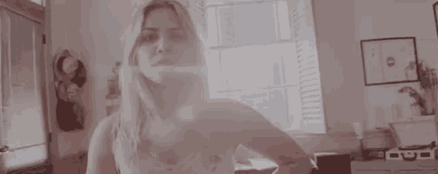a woman is standing in front of a window in a room with her hands on her hips .