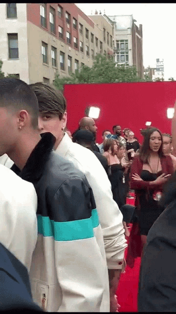 a group of people standing on a red carpet with a woman wearing a lanyard