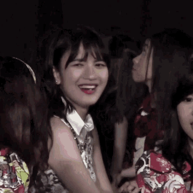 a group of girls are sitting in a dark room and one girl is smiling