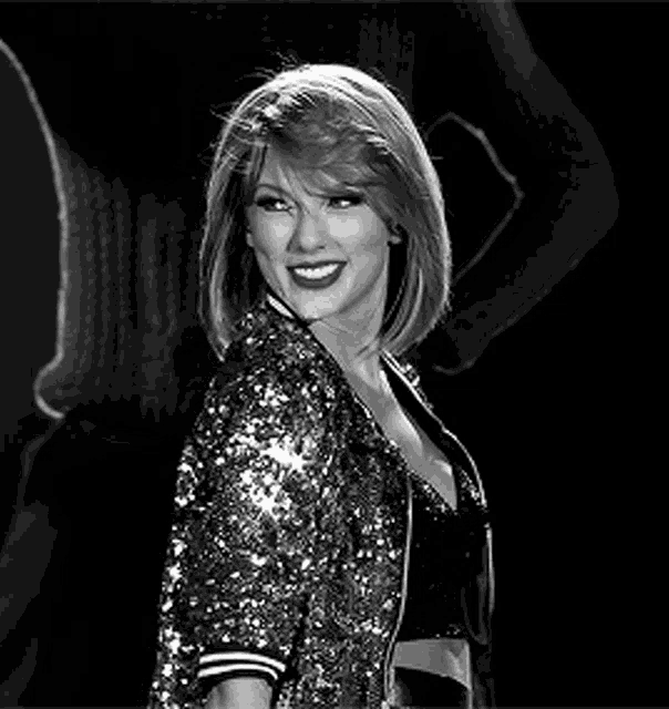 a black and white photo of a woman wearing a sequined jacket and a crop top .