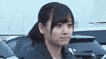 a close up of a woman 's face with a ponytail and a car in the background .