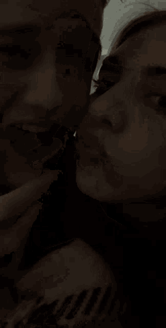 a blurry picture of a man and a woman kissing .