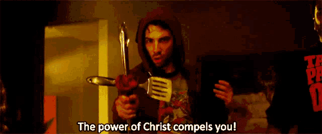 a man in a red hoodie is holding a spatula and a knife and says the power of christ compels you