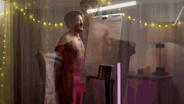 a man without a shirt is standing in front of a mirror with a light on it