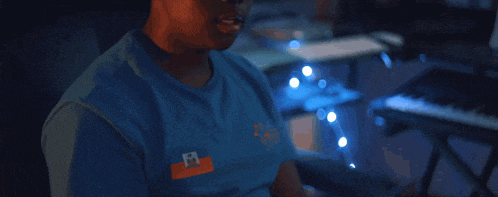 a man wearing a blue shirt with the letter m on the front