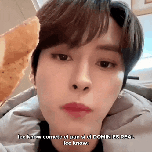 a close up of a person 's face with the words lee know comete el pan si el domin es real on the bottom