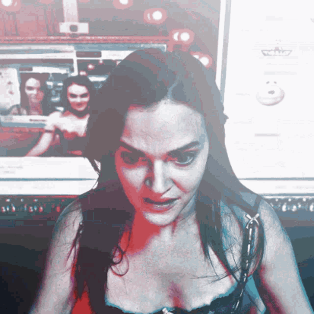 a woman in a bra is looking at the camera in front of a computer screen