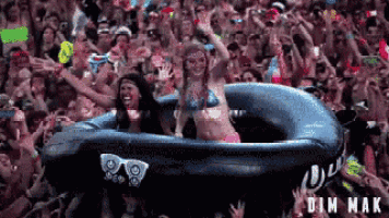 a crowd of people are gathered around a large inflatable raft that says dim mak