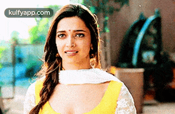 a close up of a woman wearing a yellow top and white dupatta .