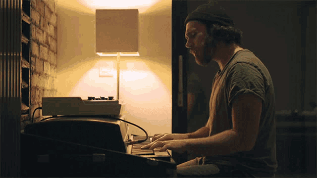 a man with a beard is typing on a keyboard in a dark room