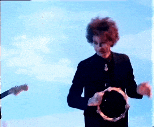 a man in a black jacket is holding a tambourine in his hands .