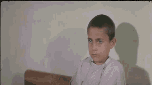 a young boy is making a funny face and pointing up
