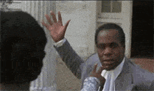 a man in a suit and tie is waving his hand in front of another man .