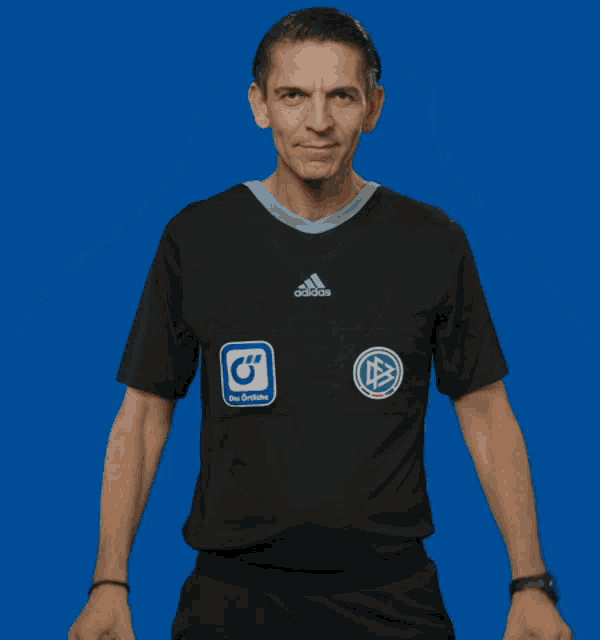a man in a black adidas shirt holds two tomatoes in front of his eyes