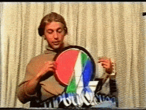 a man is holding a colorful object in his hands in front of a sign .
