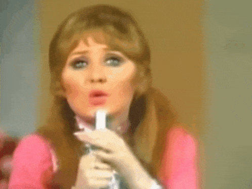 a woman in a pink dress is singing into a microphone .