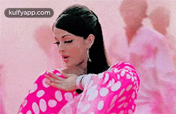 a woman in a pink polka dot dress is holding a pink pillow .