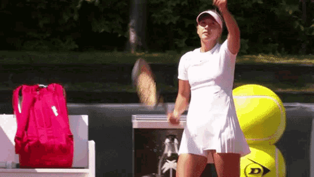 a woman in a white dress is holding a tennis racquet