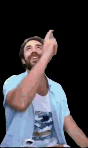 a man in a blue shirt is pointing up with his arms outstretched