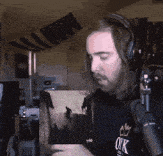 a man wearing headphones and a shirt that says ok looks at a picture