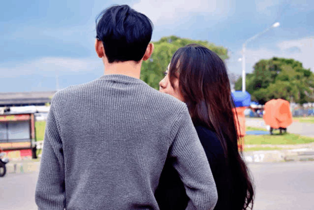 a man in a grey sweater is standing next to a woman in a black dress