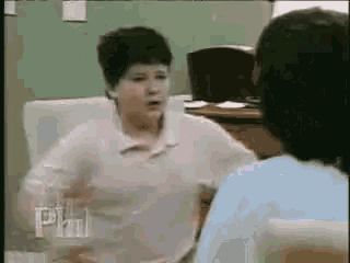 a woman in a pink shirt is talking to another woman in a room .