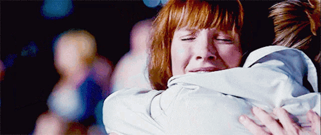 a woman with red hair is hugging a man