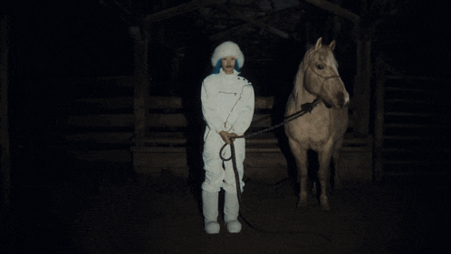 a woman with blue hair standing next to a horse