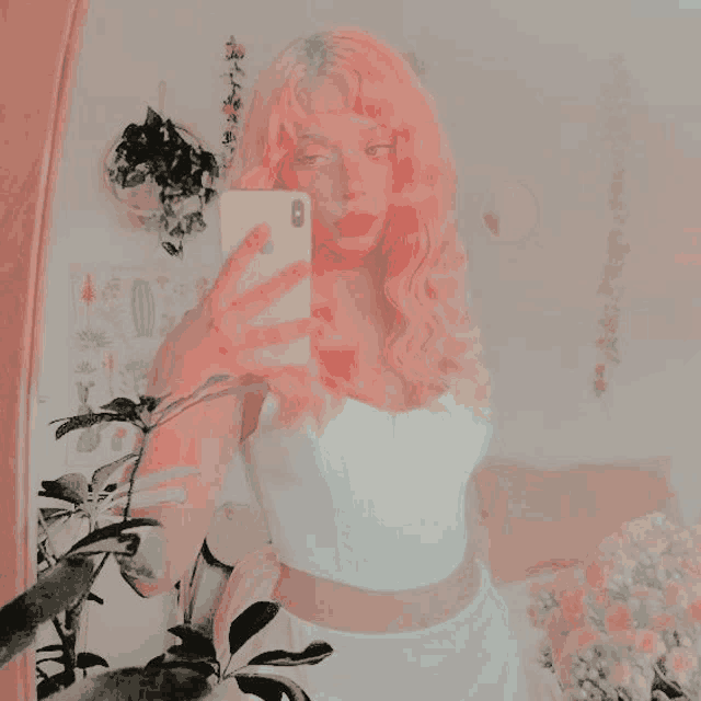 a girl with pink hair is taking a selfie with her iphone