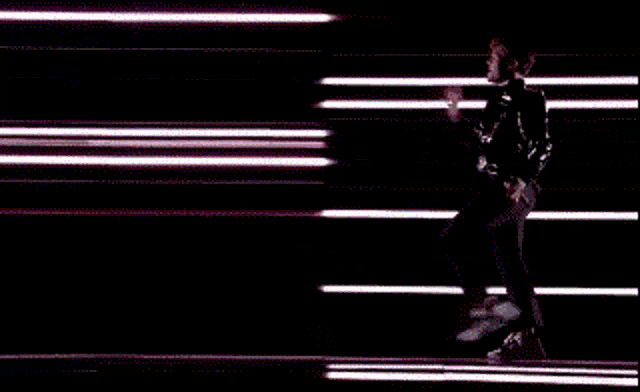 a person is dancing in front of a row of neon lights