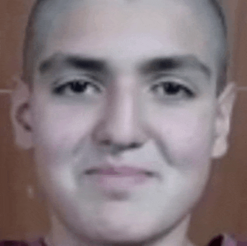a close up of a person 's face with a shaved head and a smile .