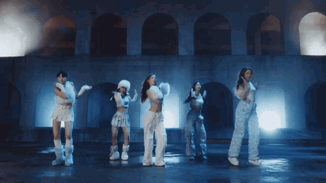 a group of women are dancing in front of a building with arches