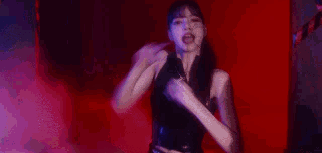 a woman in a black tank top is fighting another woman in a red room
