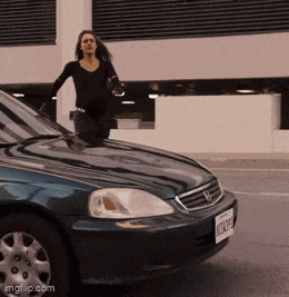 a woman stands on the hood of a blue honda