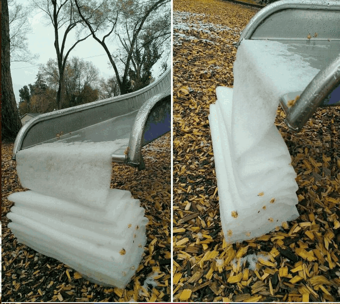 a slide is covered in snow and leaves and a stack of ice is on the ground