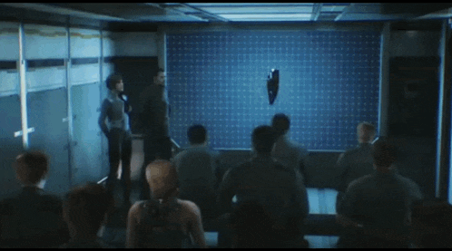 a group of people are sitting in front of a large screen with a eagle on it