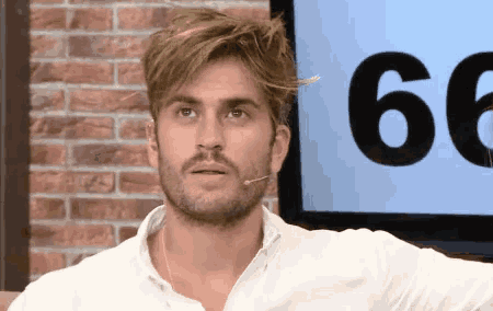a man with a beard stands in front of a screen that says 66