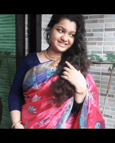 a woman wearing a red saree and a blue blouse is smiling