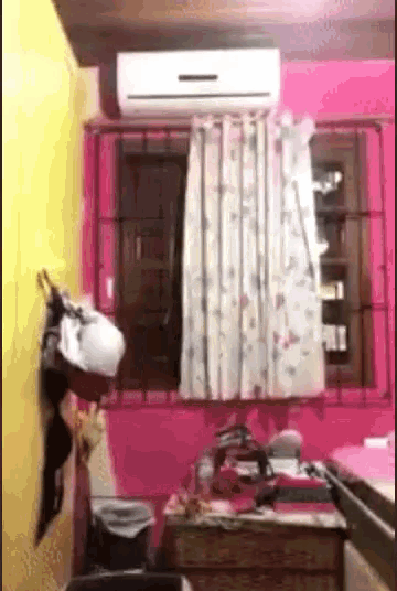 a room with pink walls and a white air conditioner on the ceiling