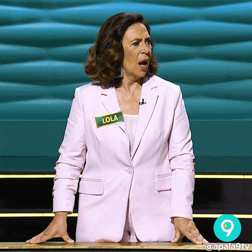 a woman in a pink suit has a name tag that says lola on it