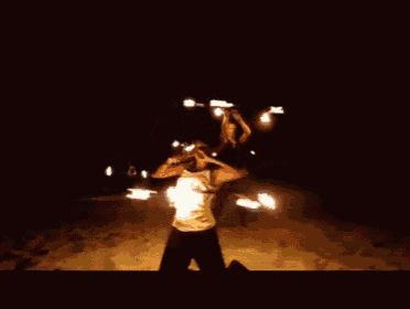 a man in a white tank top is holding a woman on his shoulders in the dark