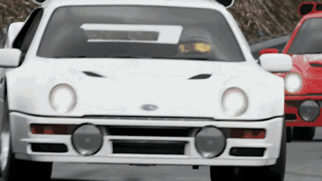 a white ford car is driving next to a red ford car