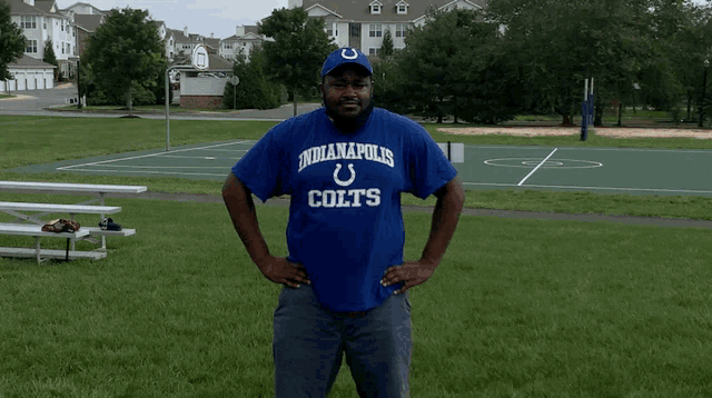 a man wearing an indianapolis colts shirt stands in front of a basketball court