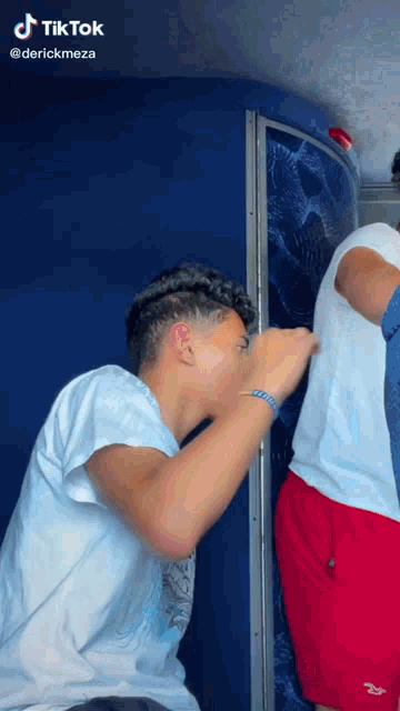 a man in a white shirt and red shorts is sitting next to a man in a white shirt and red shorts .