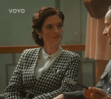 a woman in a black and white sweater is sitting next to a man in a white shirt .