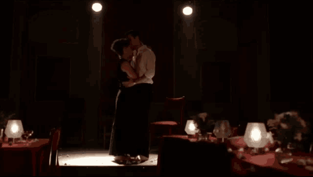 a man and a woman are dancing on a stage in a dark room