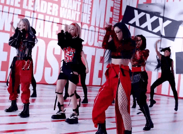 a group of women are dancing in front of a sign that says " xxx "